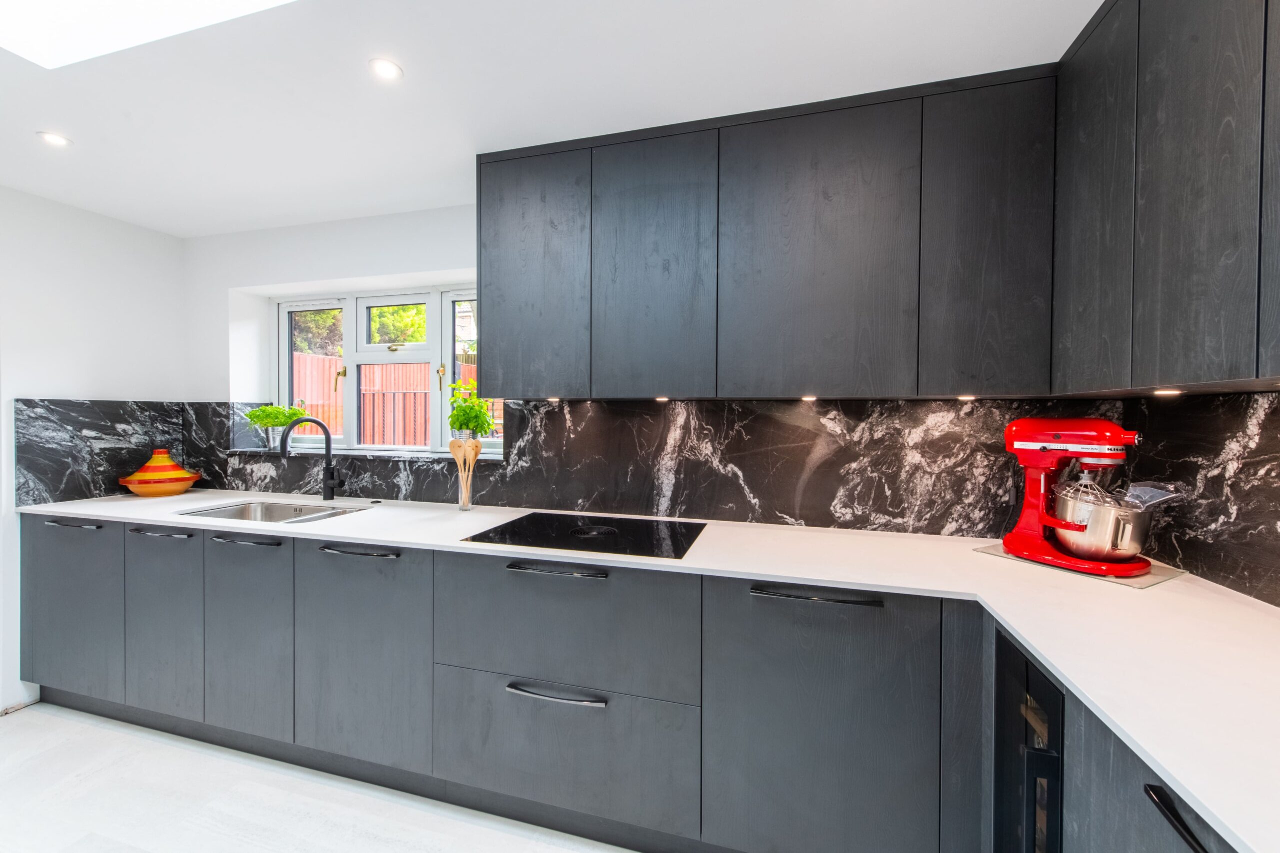 Dark modern kitchen with black cabinets and marble splashback designed by Ornate Kitchens
