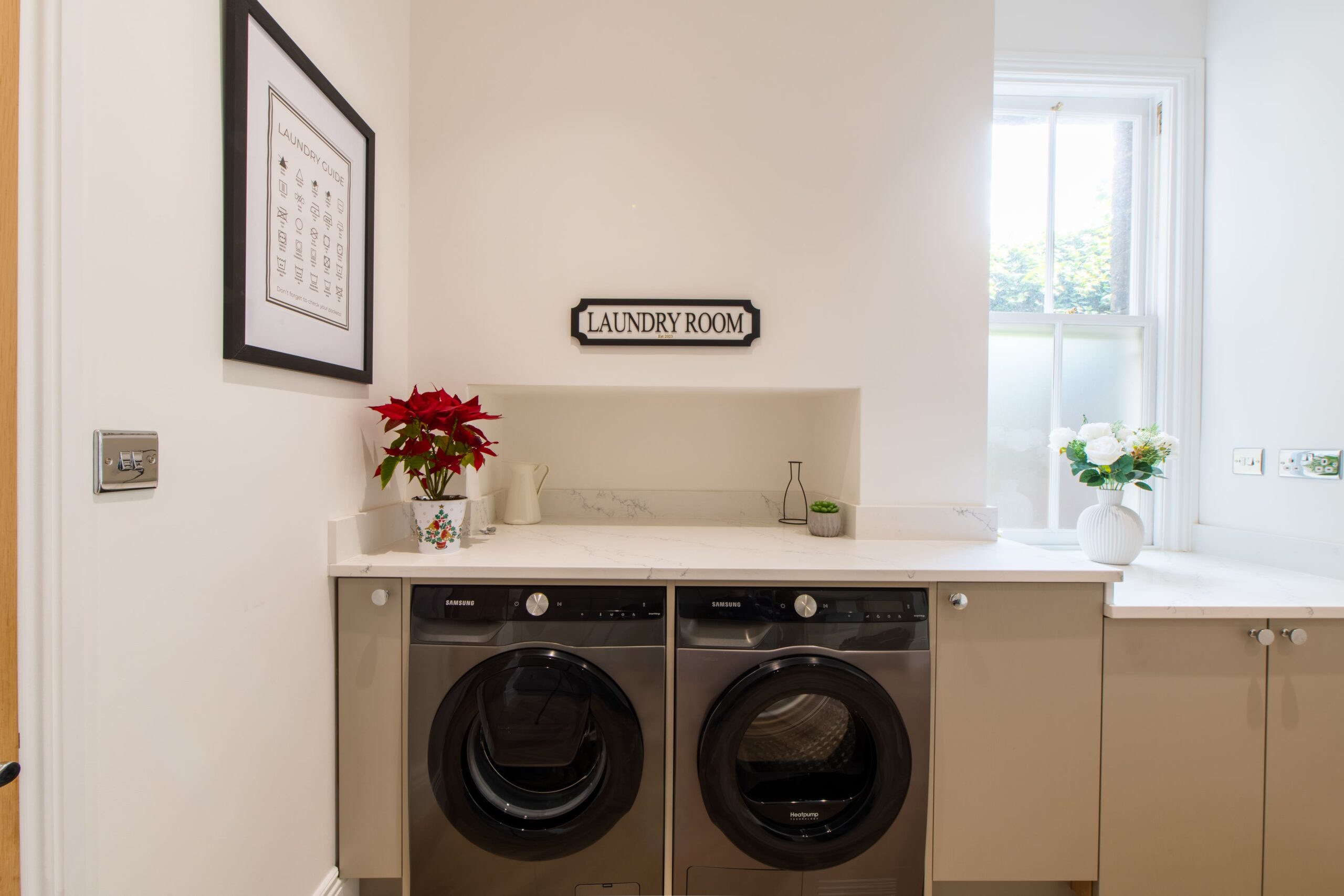 Utility room with washing machine, tumble dryer, fitted cabinets and white worktop