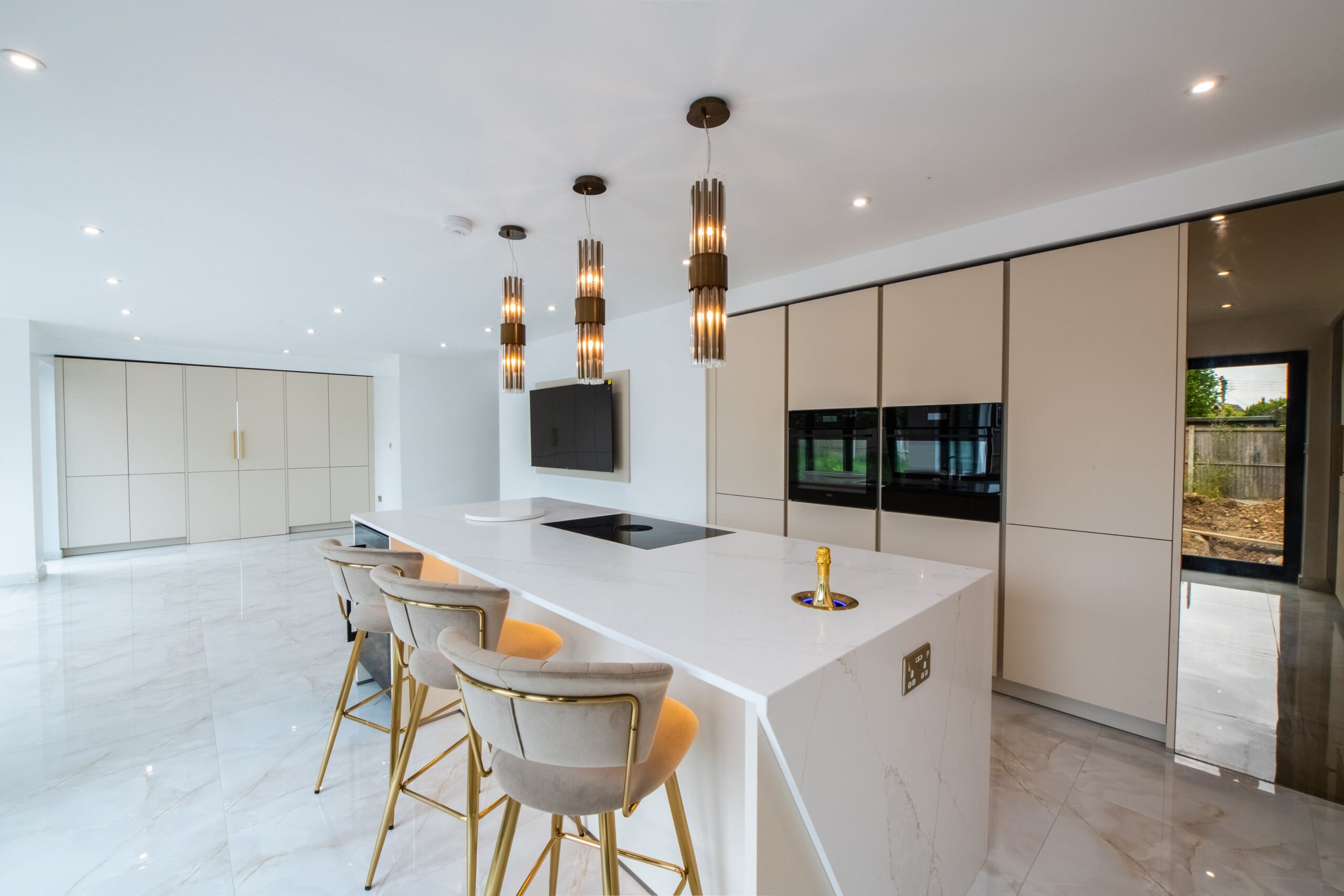 Luxury open plan kitchen with large island, built in appliances and tall storage cabinets