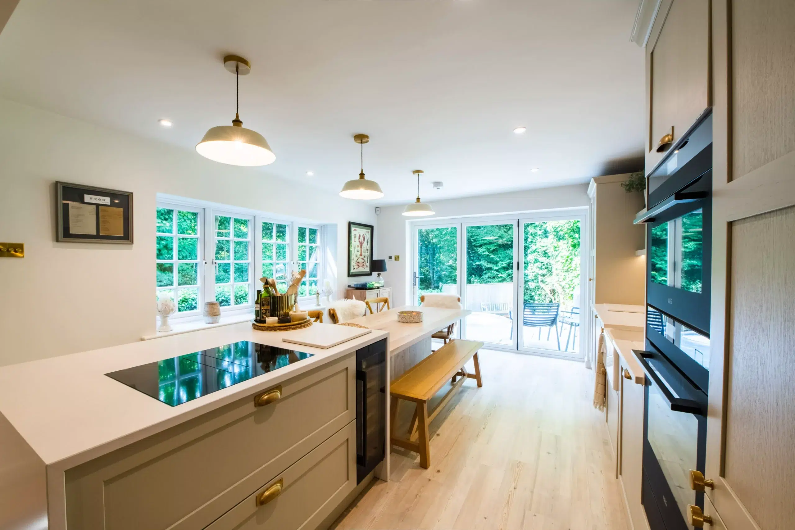Spacious family kitchen renovation with large island, dining bench and garden views by Ornate Kitchens