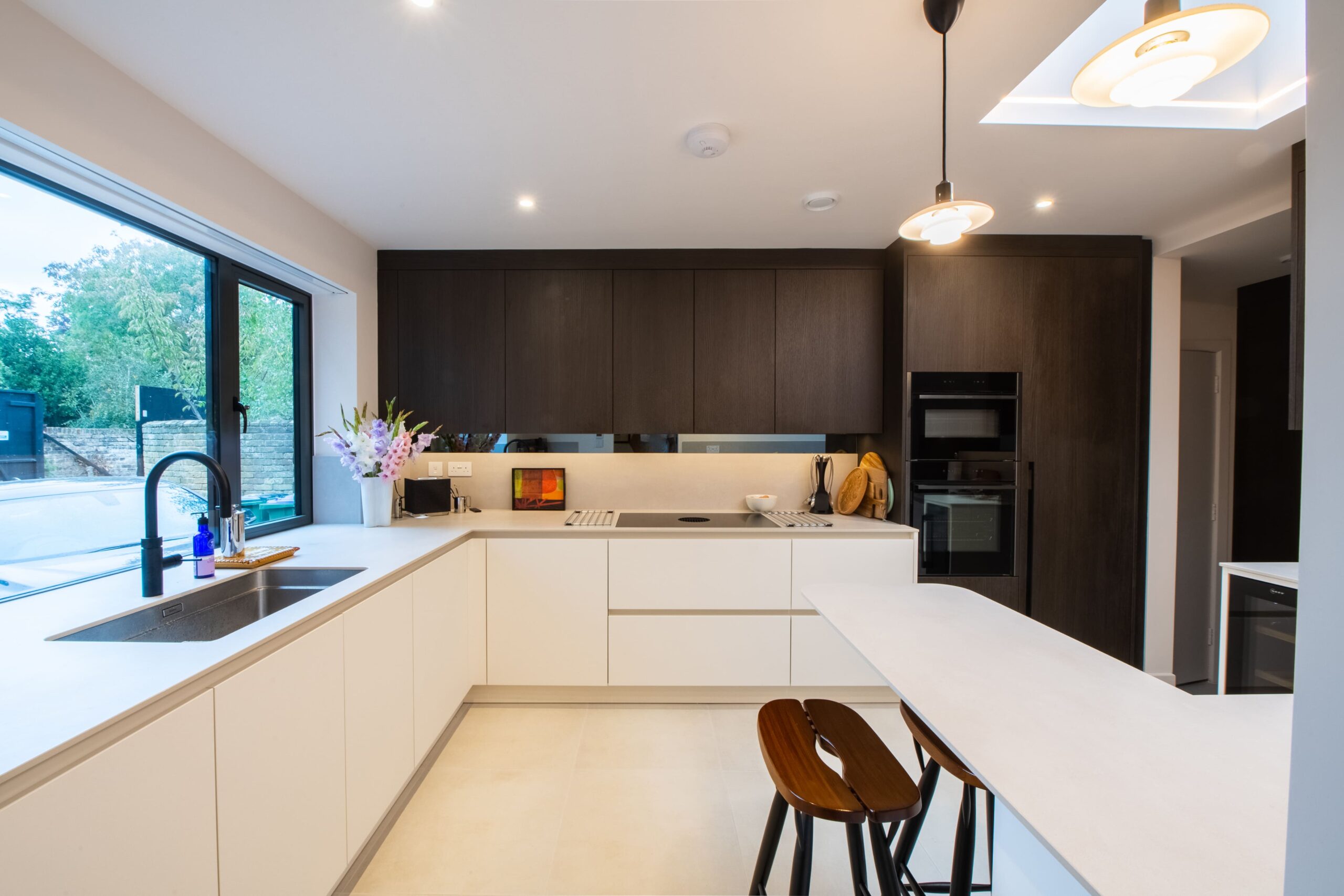 Two-tone kitchen with white base units and dark wood wall cabinets by Ornate Kitchens