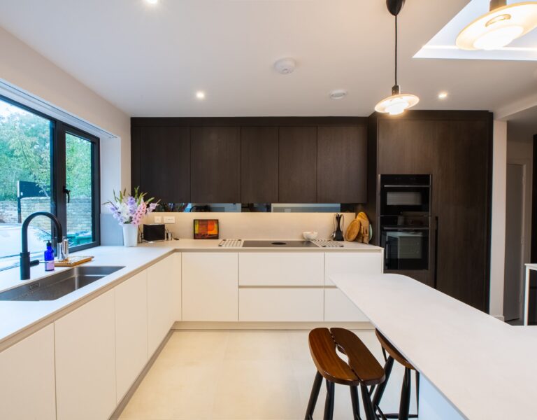 Two-tone kitchen with white base units and dark wood wall cabinets by Ornate Kitchens