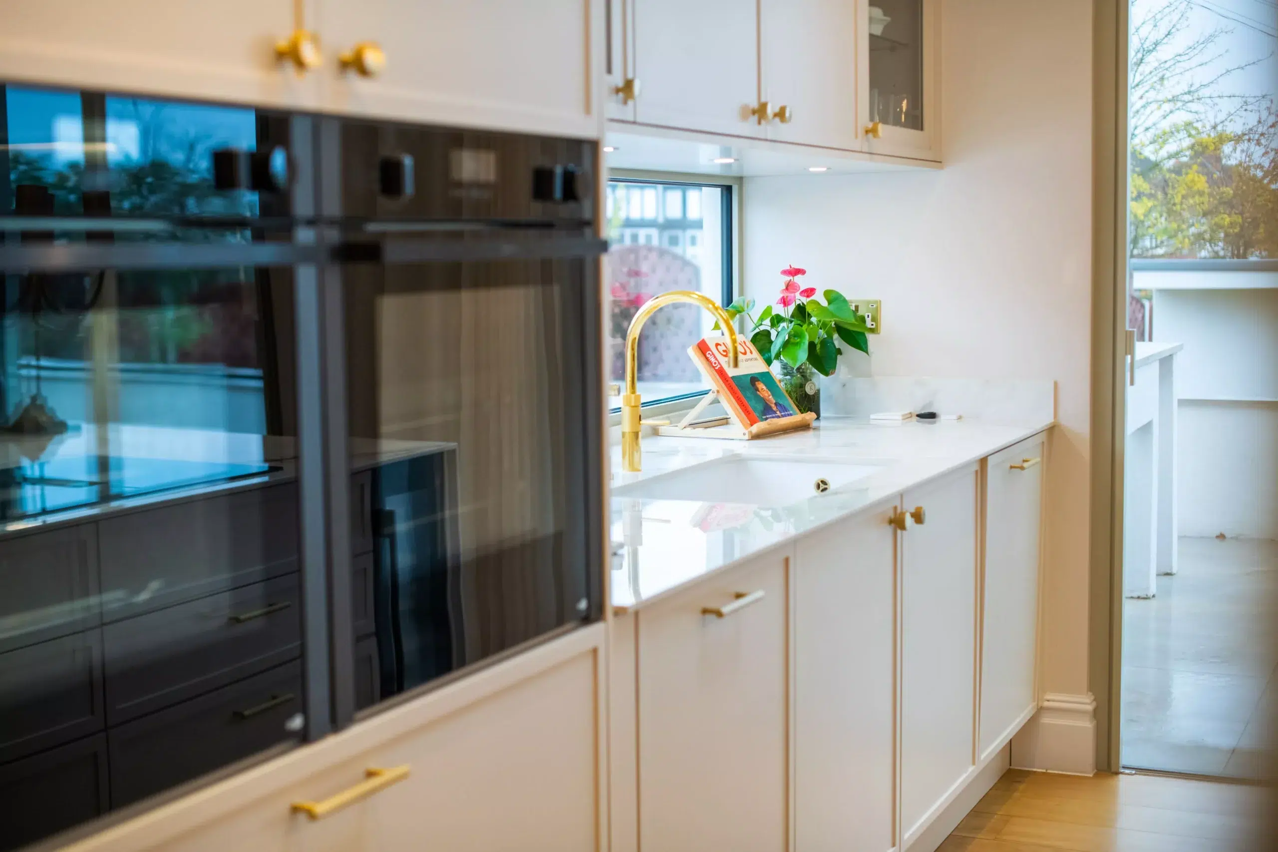 Bright shaker kitchen with white quartz worktops and brass fixtures during renovation by Ornate Kitchens