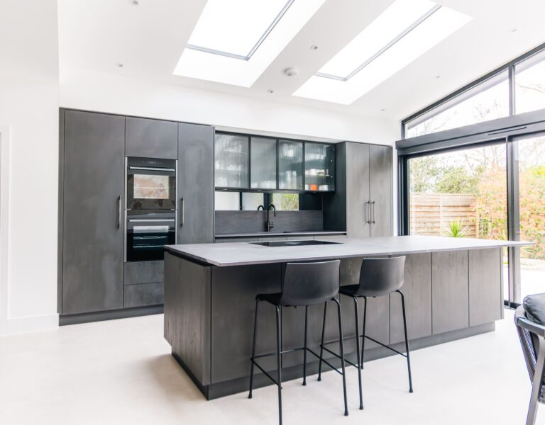 Open plan modern kitchen with dark cabinetry, large island and skylights designed by Ornate Kitchens